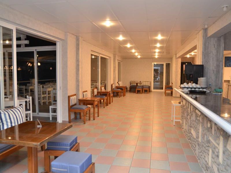 Velká světlá hotelová chodba s posezením a výhledem ven.