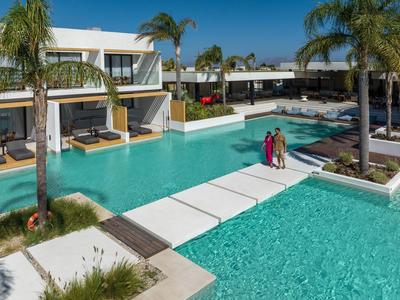 Moderner Hotelpool mit Sonnenliegen und Palmen unter klarem blauem Himmel