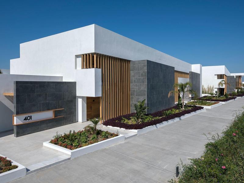 Modern white houses with clean lines and landscaped gardens under clear sky.