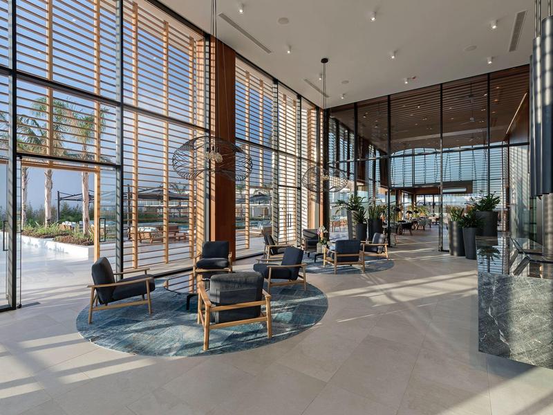 Modern hotel lobby with large windows, seating area, and abundant natural light.