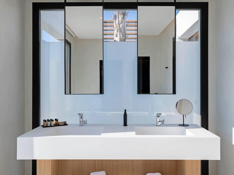 Modern bathroom with double sink, large mirrors, and white towels.