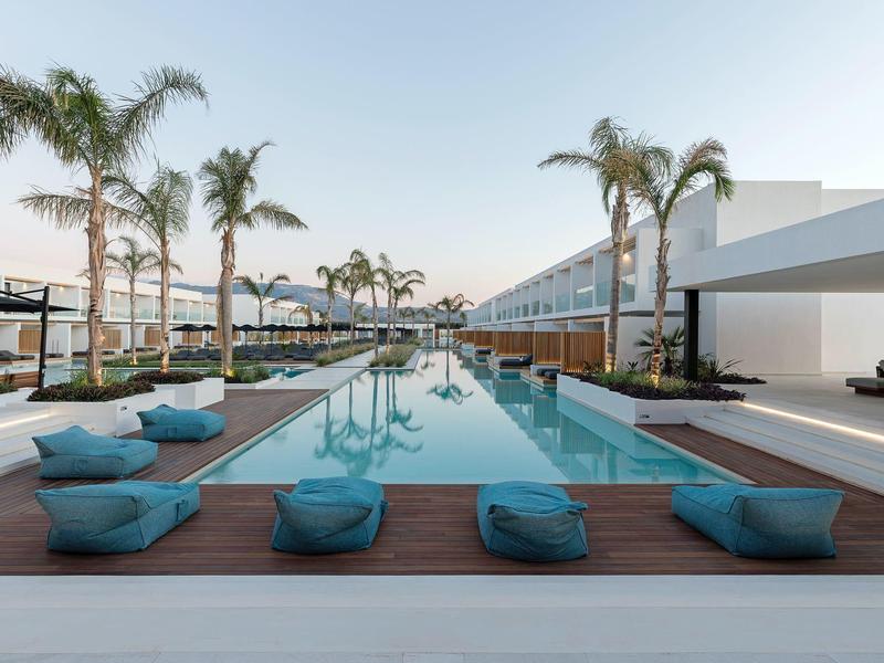 Modern pool area with loungers and palm trees at a luxury hotel.