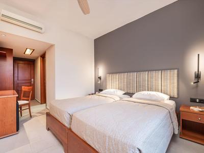 Modern eingerichtetes Hotelzimmer mit zwei Einzelbetten, Holzmöbeln und warmem Licht.