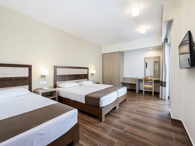 Helles Hotelzimmer mit zwei Betten, Fernseher an der Wand und Schreibtisch mit Spiegel.