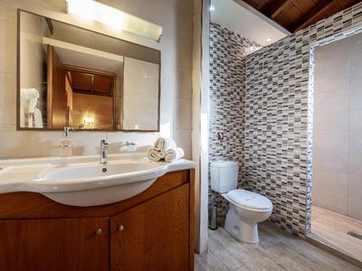 Modernes Badezimmer mit Waschtisch, Spiegel, Toilette und ebenerdiger Dusche mit Mosaikfliesen.