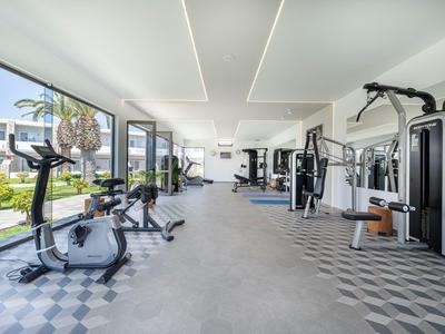 Heller Fitnessraum mit modernen Trainingsgeräten und großem Fenster mit Gartenblick.