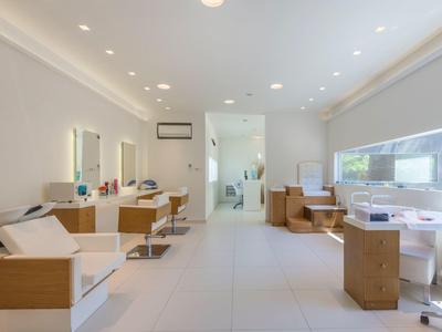 Moderne Kosmetik- oder Friseureinrichtung mit weißen Wänden, Stühlen, Spiegeln und viel Tageslicht.