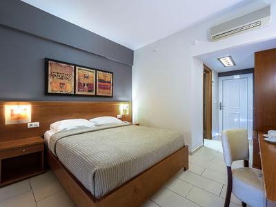 Modern eingerichtetes Hotelzimmer mit Doppelbett, zwei Nachttischen und Arbeitsplatz.