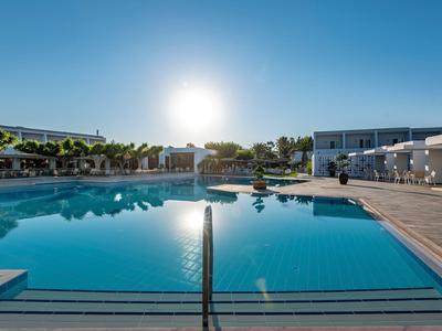 Moderner Hotelpool bei Sonnenuntergang mit klarem Wasser und Liegestühlen.