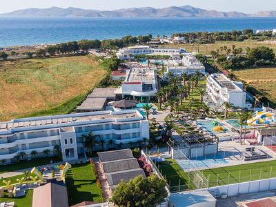 Große Hotelanlage mit Pool, Sportplätzen und Blick auf das offene Meer und Inseln im Hintergrund.