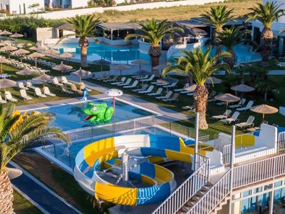 Blick auf einen Poolbereich mit Rutschen, Sonnenliegen und Sonnenschirmen in einer Hotelanlage.