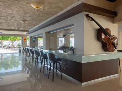 Moderner Hotelbarbereich mit Hockern und dekorativer Gitarre an der Wand.