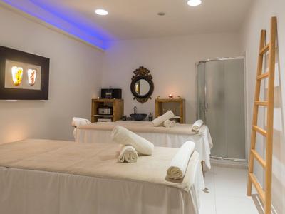 Ein helle Behandlungsraum mit zwei Massageliegen, warmem Licht und Spa-Elementen.