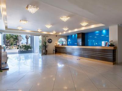 Helle Hotellobby mit großem Empfangstresen und moderner Innenausstattung.