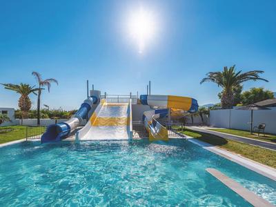 Wasserpark mit Wasserrutschen und Pool in sonniger Umgebung mit Palmen.