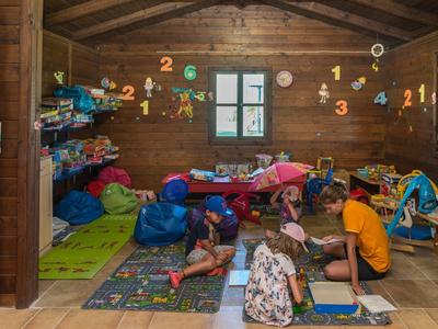 Kinder spielen und malen in einem gemütlichen, bunt dekorierten Holzzimmer mit Spielzeug und Büchern.