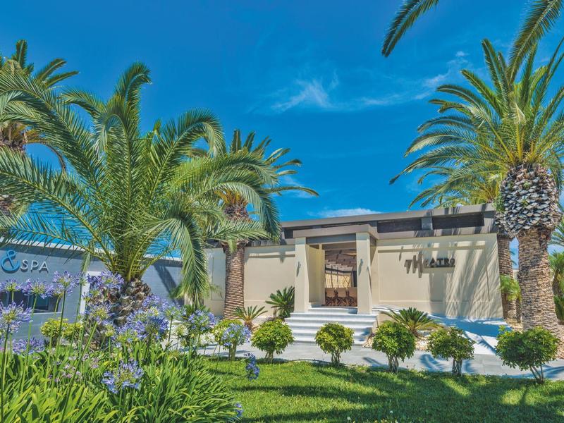 Casa de vacaciones rodeada de palmeras y jardín con cielo despejado y azul