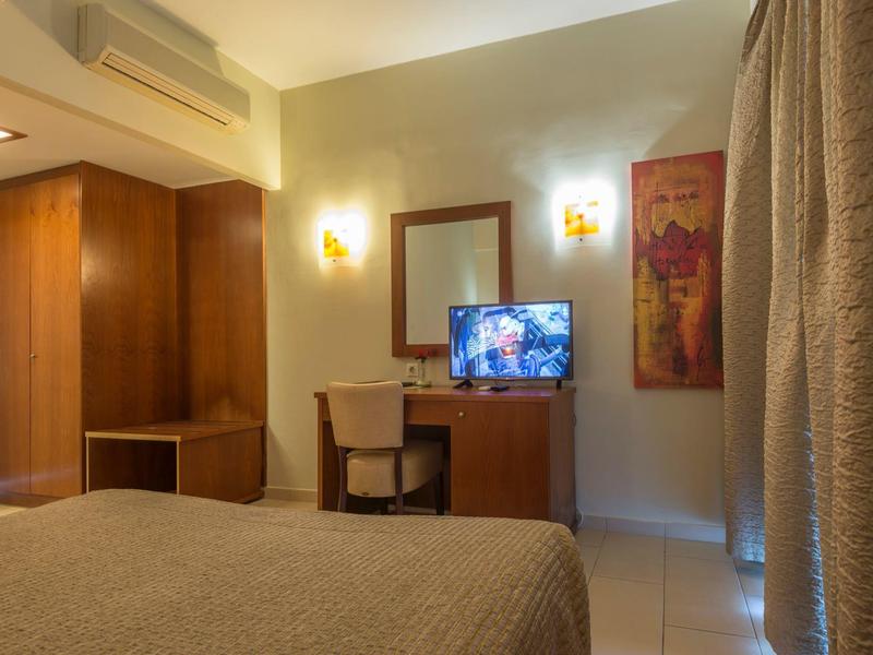 Habitación de hotel acogedora con escritorio, silla, televisor y luces cálidas en la pared.