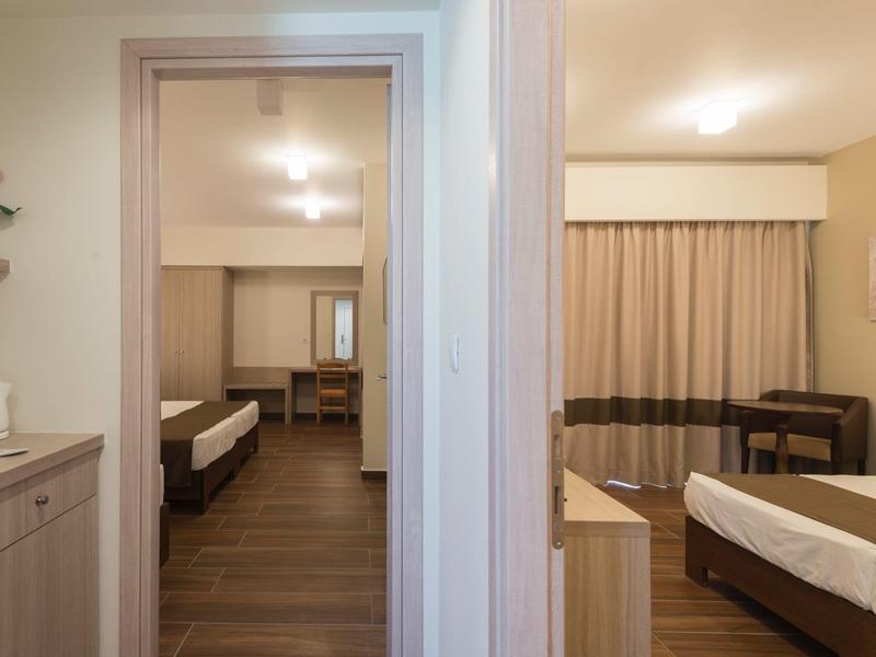 Dos habitaciones de hotel con camas, escritorios y estilo de iluminación cálido.