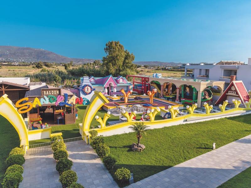 Gran parque al aire libre con parque infantil y toboganes en un resort hotelero soleado.
