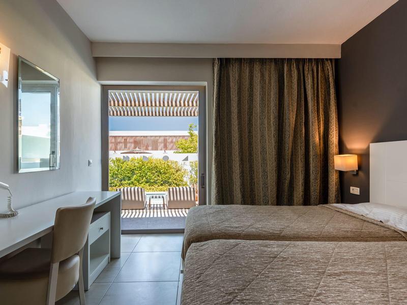 Habitación de hotel moderna con cama doble, escritorio y balcón con vista exterior.