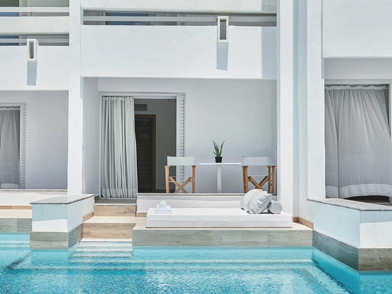 Días modernos en un hotel con paredes blancas y piscina azul bajo cielo despejado.