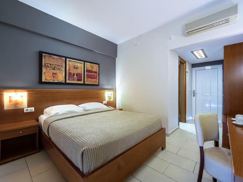 Habitación de hotel moderna con cama doble, mesitas, escritorio y baño contiguo