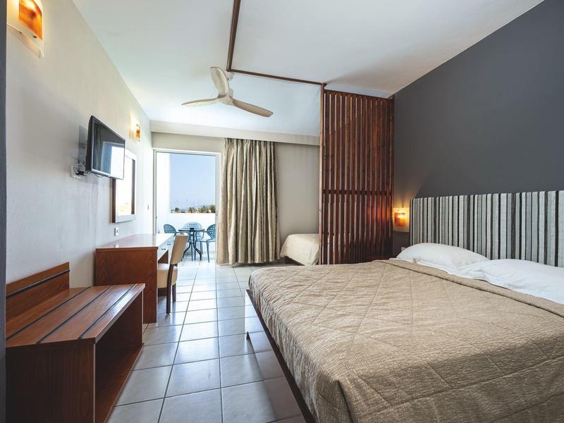 Habitación de hotel moderna con cama grande, terraza y vista al mar.