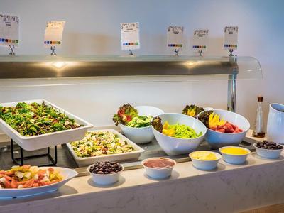 Buffet mit Salaten, Dips und kleinen Schalen, alles in weißen Servierschalen arrangiert.