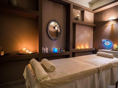 Ein ruhiger Massageraum mit gedämpftem Licht, zwei Massageliegen und brennenden Kerzen.