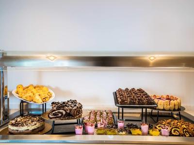 Buffet mit verschiedenen kleinen Kuchen, Gebäck und Muffins auf weißen Tellern und Metallständern.
