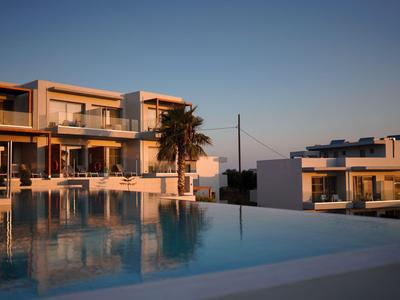 Moderner Hotelkomplex mit Pool und Palmbaum bei Sonnenuntergang.