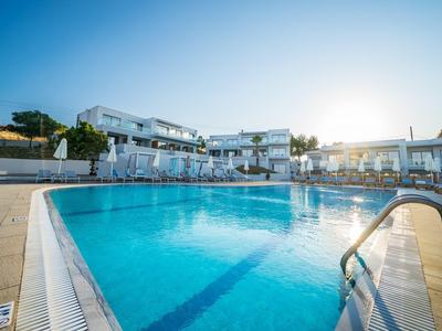 Großer Außenpool mit klarem Wasser und moderner Hotelanlage im Hintergrund bei sonnigem Wetter.