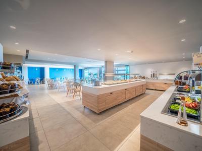 Heller Frühstücksraum mit Buffet und Sitzbereichen in einem Hotel.