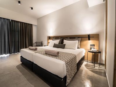 Modernes Hotelzimmer mit zwei Betten, Nachtisch und Vorhängen bei gedämpftem Licht.