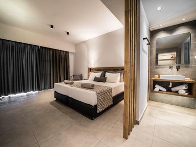 Modernes Hotelzimmer mit Doppelbett, neutralen Farben und offenem Badezimmerbereich.