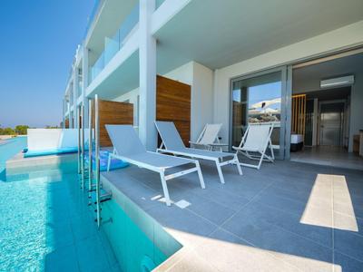 Moderne Terrasse mit Liegestühlen und direktem Zugang zum Pool in einem Hotel.