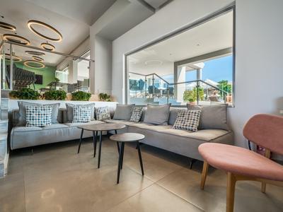 Modern eingerichteter Hotellobby mit bequemen Sofas, Tischen und großen Fenstern mit Blick auf Terrasse.