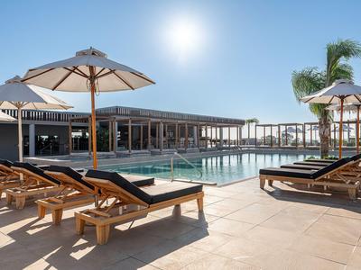 Ein Hotelpool mit Liegestühlen und Sonnenschirmen unter klarem Himmel am sonnigen Tag.
