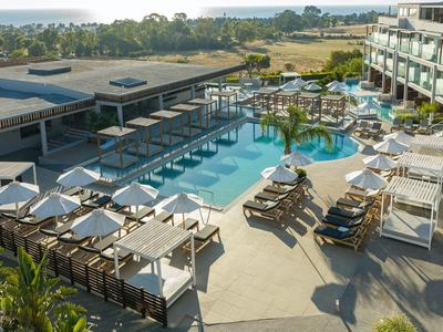 Moderner Hotelpool mit Liegestühlen und Sonnenschirmen in sonniger Landschaft.