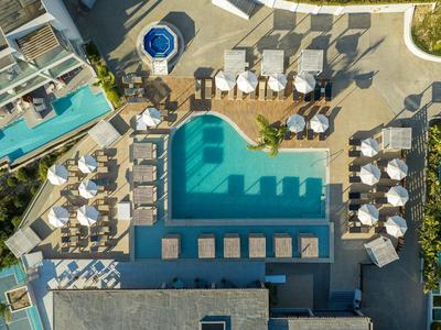 Vogelperspektive eines Hotels mit Schwimmbad, Liegestühlen und Sonnenschirmen.