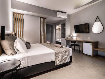 Modernes Hotelzimmer mit Bett, Fernseher, Schreibtisch und Klimaanlage in neutralen Farben.