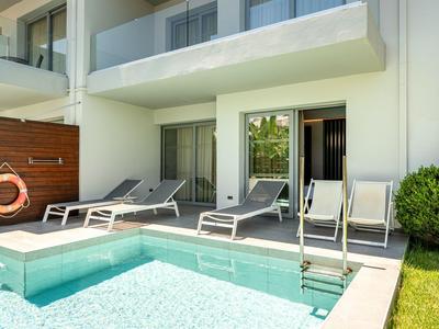 Moderner Hotelpool mit Liegestühlen und direktem Zugang zu Zimmerbalkonen.