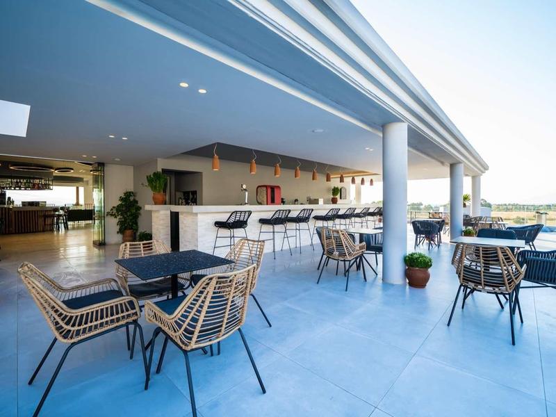 Zonnig buitenterras van het hotel met moderne zitplaatsen en tafels onder een overdekte dak.