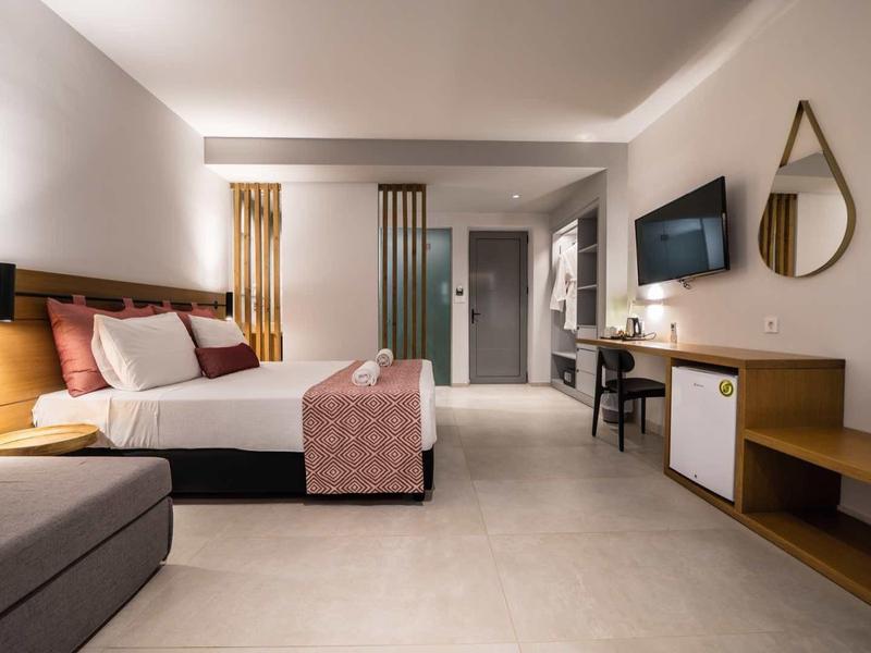 Moderne hotelkamer met kingsize bed, tv aan de muur, bureau en neutrale tinten in een ruime ruimte.