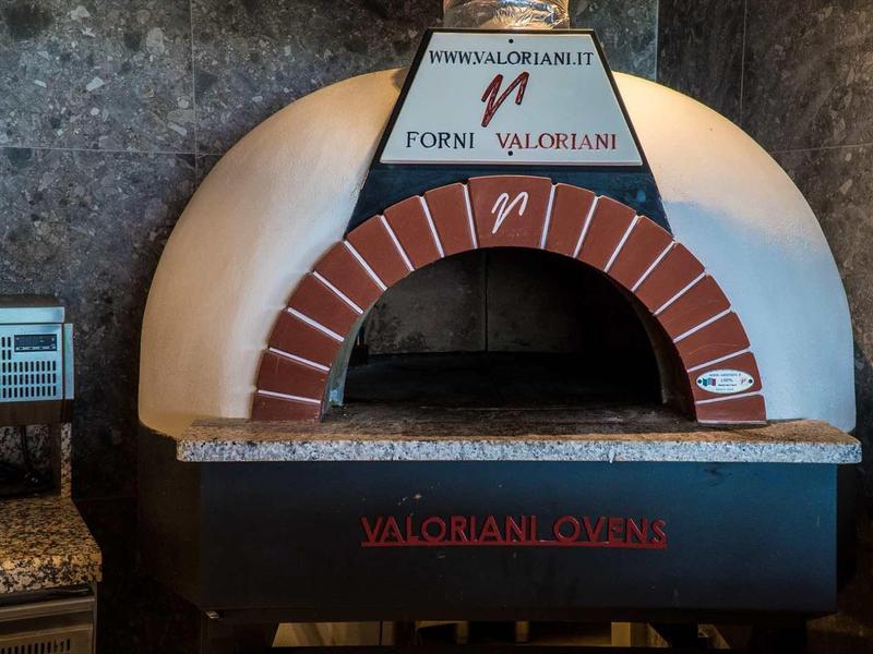 Steenoven voor pizza met bakstenen boog in een rustieke keukenomgeving.