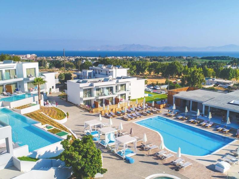 Modern resort met meerdere zwembaden, witte gebouwen en ligstoelen aan de kust.