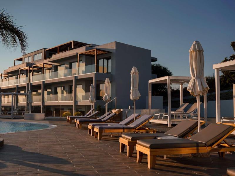 Modern hotel met ligstoelen en parasols bij het zwembad bij zonsondergang.