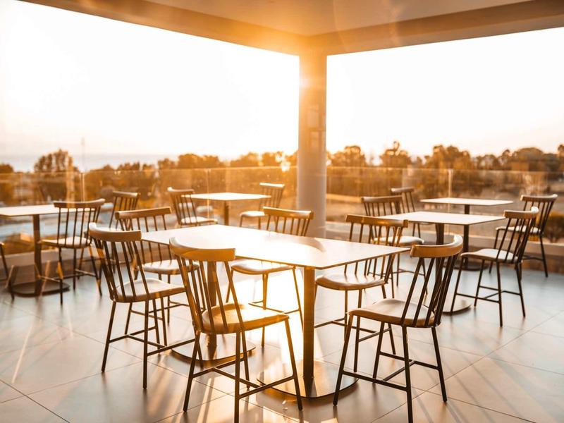 Leeg buitenterras met houten tafels en stoelen bij zonsondergang.