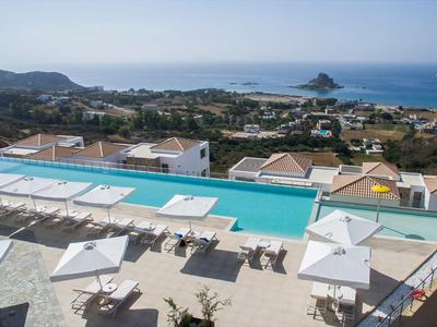 Moderner Außenpool mit Liegestühlen und Sonnenschirmen, im Hintergrund Küstenlandschaft und Meer.